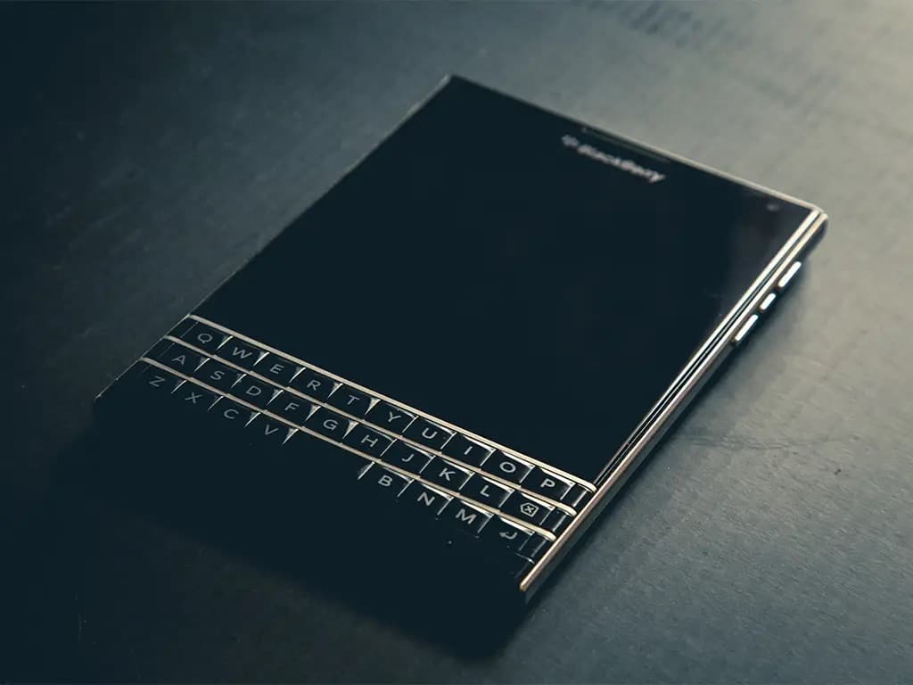 a blackberry phone placed on a table with a blank screen