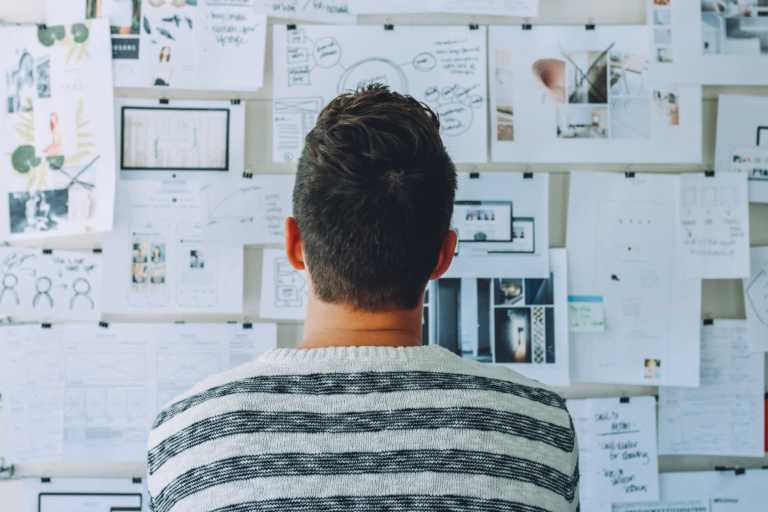 man looking over a design plan all over his wall