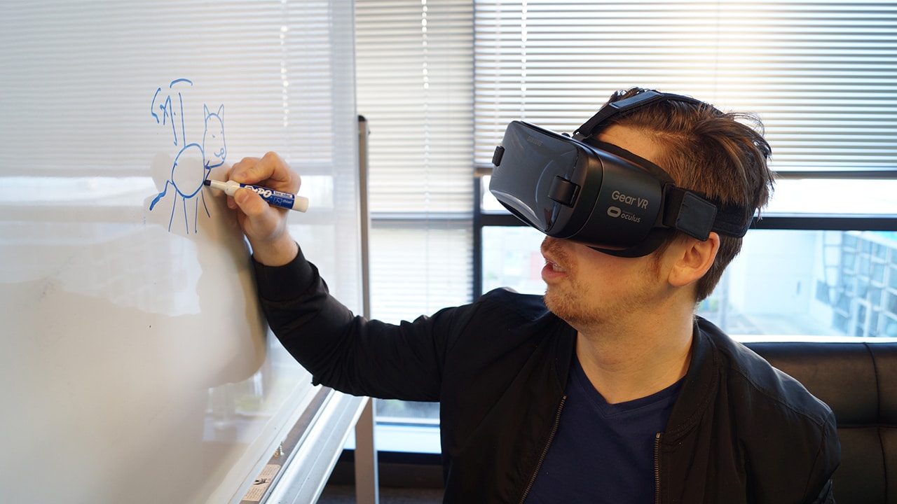 man wearing VR goggles while writing on whiteboard